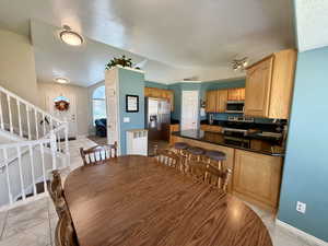 Dining room featuring a textured ceiling, stairway, lofted ceiling, and light tile patterned floors