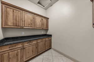 Laundry room featuring light tile patterned floors and baseboards