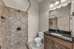 Bathroom with a tile shower, vanity, and light tile patterned flooring
