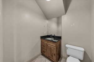 Bathroom featuring vanity, light tile patterned floors, and vaulted ceiling