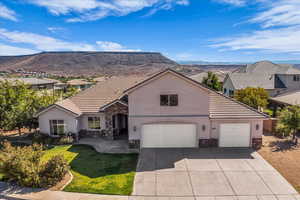 View of front facade featuring stone siding, stucco siding, concrete driveway, a front lawn, and a tiled roof