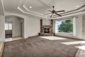 Unfurnished living room with a tray ceiling, plenty of natural light, and light carpet