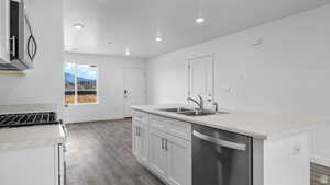 Kitchen featuring light countertops, stainless steel appliances, a kitchen island with sink, white cabinets, and recessed lighting