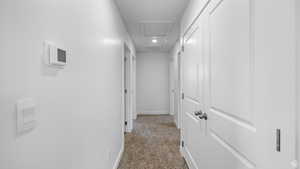 Corridor featuring light colored carpet and attic access