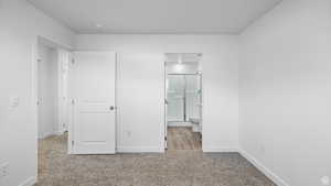 Unfurnished bedroom featuring light colored carpet and ensuite bath