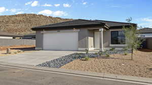 Prairie-style home with stucco siding, driveway, an attached garage, a tiled roof, and a mountain view