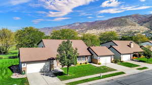 View of front of house featuring concrete driveway, a front yard, a garage, and a mountain view