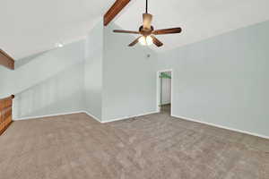 Spare room featuring beamed ceiling, light carpet, ceiling fan, and high vaulted ceiling
