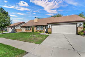 Single story home featuring brick siding, a front yard, concrete driveway, a garage, and a chimney