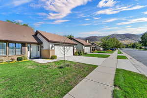 View of green lawn featuring driveway, a garage, and a mountain view