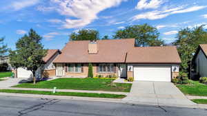 View of front of property with a front yard, an attached garage, brick siding, concrete driveway, and roof with shingles
