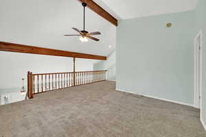 Unfurnished room featuring beamed ceiling, light colored carpet, high vaulted ceiling, and ceiling fan