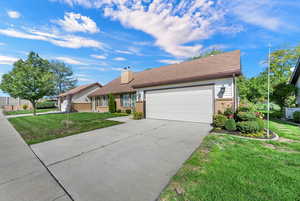 Single story home featuring a front lawn, brick siding, concrete driveway, a chimney, and a garage