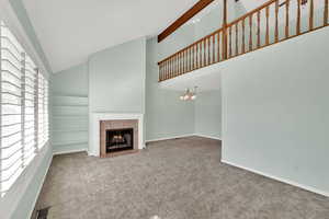 Unfurnished living room featuring high vaulted ceiling, carpet, and a fireplace