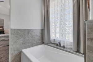 Full bath featuring healthy amount of natural light and a bath