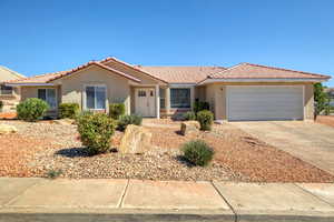View of front facade featuring stucco siding, driveway, an attached garage, and a tiled roof