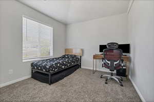 Carpeted bedroom featuring baseboards and an office area