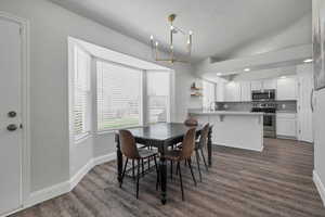 Dining room with dark wood-style floors, a chandelier, a textured ceiling, and recessed lighting