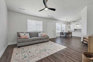 Living room with ceiling fan, dark wood-type flooring, a textured ceiling, a chandelier, and vaulted ceiling
