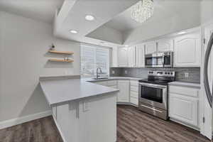 Kitchen featuring white cabinets, stainless steel appliances, open shelves, recessed lighting, and light countertops