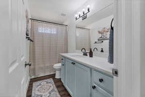 Bathroom featuring vanity, dark wood-style floors, a textured ceiling, and shower / tub combo