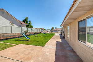 Fenced backyard featuring a playground and a patio