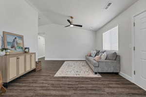 Living area featuring vaulted ceiling, dark wood-style floors, ceiling fan, and a textured ceiling