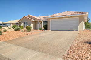 View of front of house featuring stucco siding, a tiled roof, driveway, and a garage