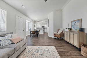 Living area with dark wood-type flooring, a chandelier, a textured ceiling, and lofted ceiling