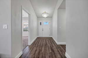 Foyer with dark wood finished floors and a chandelier