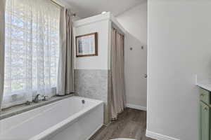 Full bathroom with a bath, dark wood-style floors, and vanity