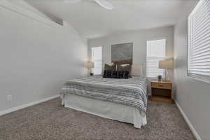 Carpeted bedroom featuring lofted ceiling and a ceiling fan