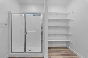 Bathroom featuring a shower stall and light wood-style floors