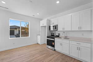 Kitchen featuring appliances with stainless steel finishes, white cabinets, light wood-style floors, and recessed lighting