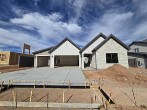 View of front facade featuring driveway, an attached garage, and stone siding