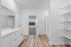 Full bathroom with a stall shower, vanity, and light wood finished floors