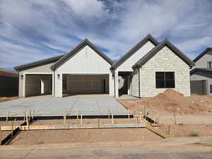 Modern farmhouse style home featuring concrete driveway, board and batten siding, a garage, and stone siding