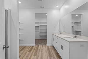 Full bath featuring a spacious closet, double vanity, light wood-style flooring, and recessed lighting