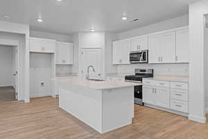 Kitchen with stainless steel appliances, white cabinets, light wood-style flooring, and recessed lighting