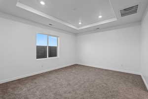 Carpeted empty room featuring a tray ceiling and recessed lighting