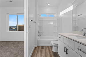Bathroom featuring shower / washtub combination, vanity, and dark wood-style flooring