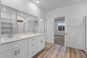 Bathroom featuring a shower stall, double vanity, and light wood-style flooring