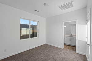 Unfurnished bedroom featuring dark carpet and connected bathroom