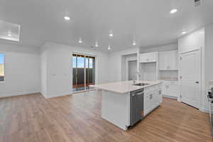 Kitchen with white cabinetry, light wood finished floors, an island with sink, and recessed lighting