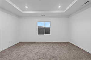Carpeted empty room featuring a raised ceiling and recessed lighting