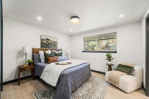 Master bedroom with light wood-type flooring and recessed lighting