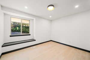 Empty bedroom 2 with light wood-style floors and recessed lighting