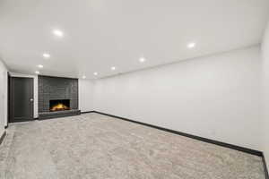 Unfurnished living room with carpet, a brick fireplace, and recessed lighting