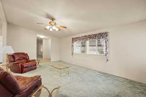 Living area with carpet and a ceiling fan
