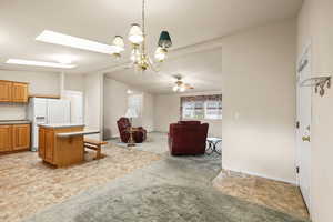 Dining room with a chandelier, vaulted ceiling, a skylight, and a ceiling fan